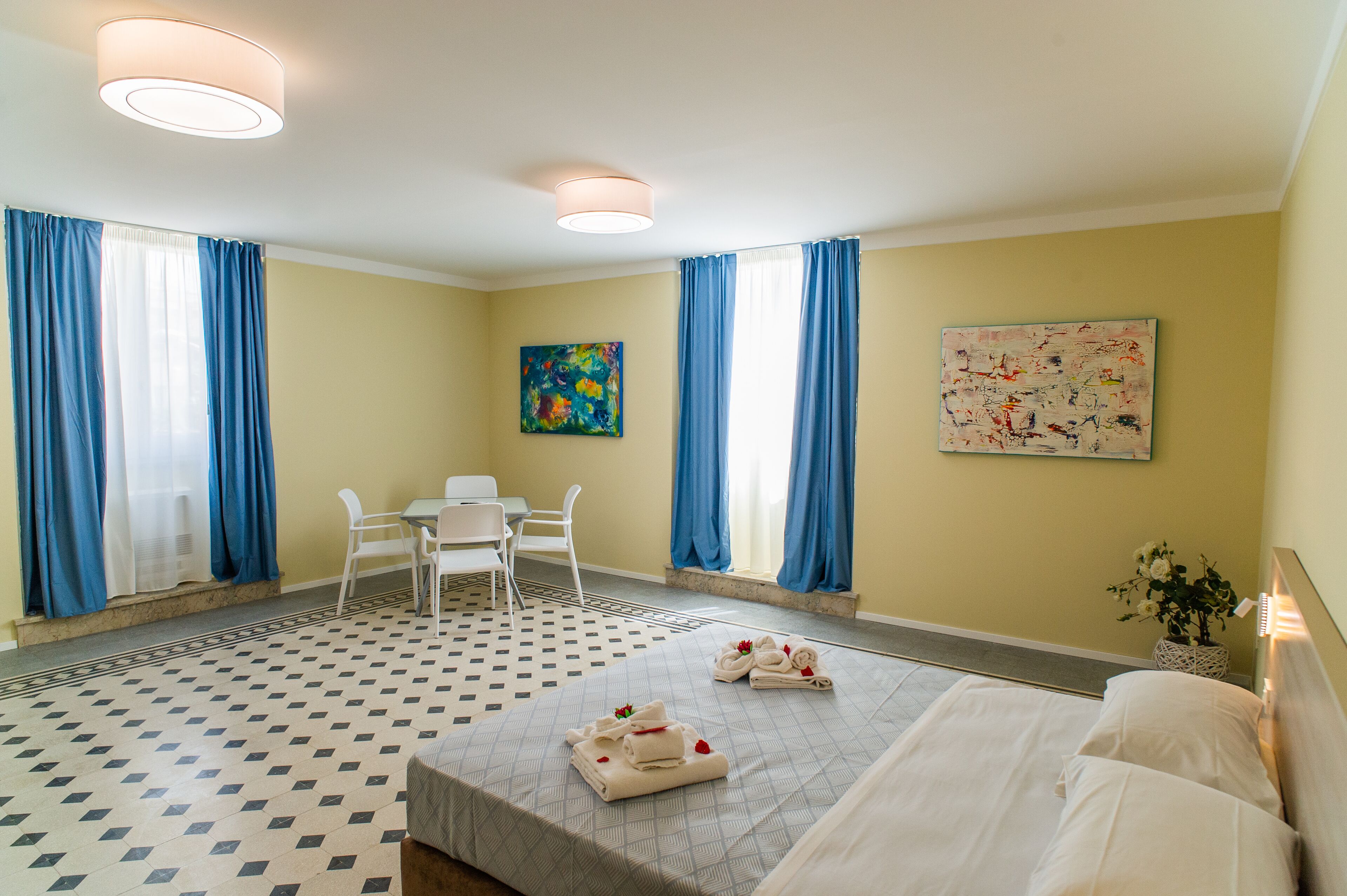 Habitación de hotel con cama, escritorio, dos sillas, una mesita y obras de arte en las paredes.