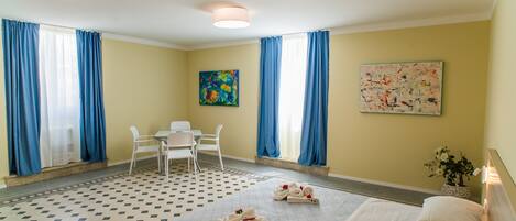 Habitación de hotel con cama, escritorio, dos sillas, una mesita y obras de arte en las paredes.