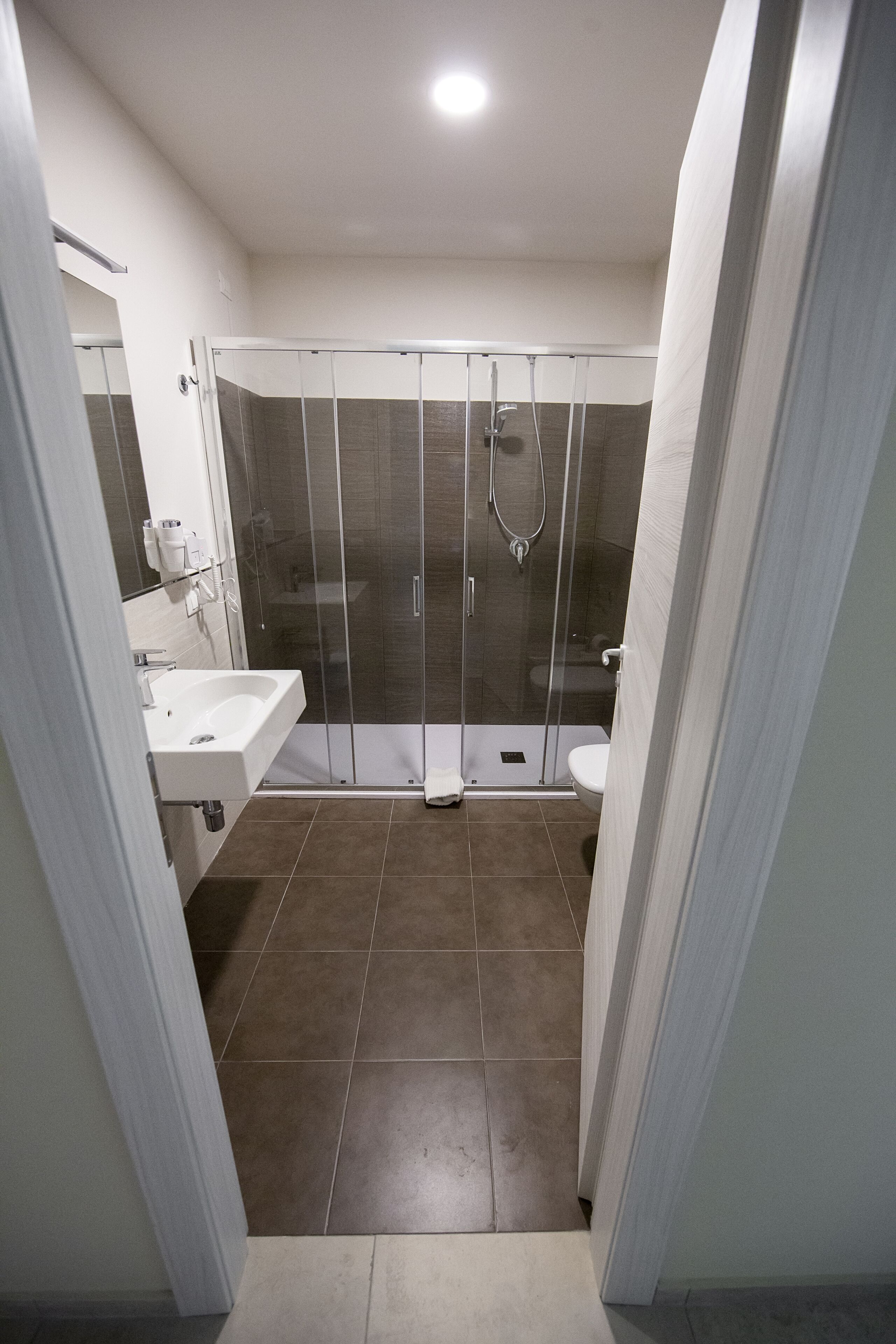 Une salle de bain moderne avec une douche à parois de verre, un lavabo blanc et des toilettes.