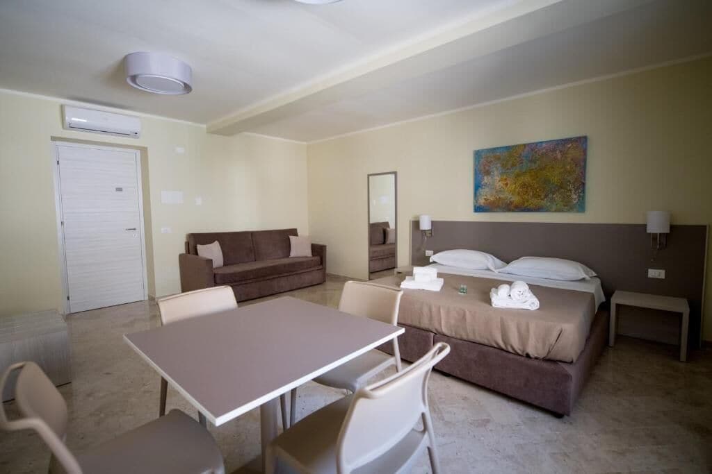 A hotel room with a bed, a sofa, a table, and chairs.