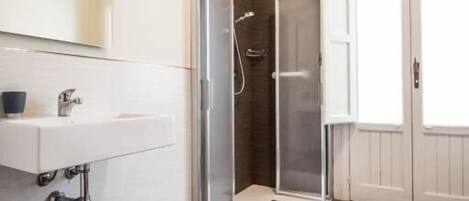 A bathroom with a shower, a sink, and a mirror.
