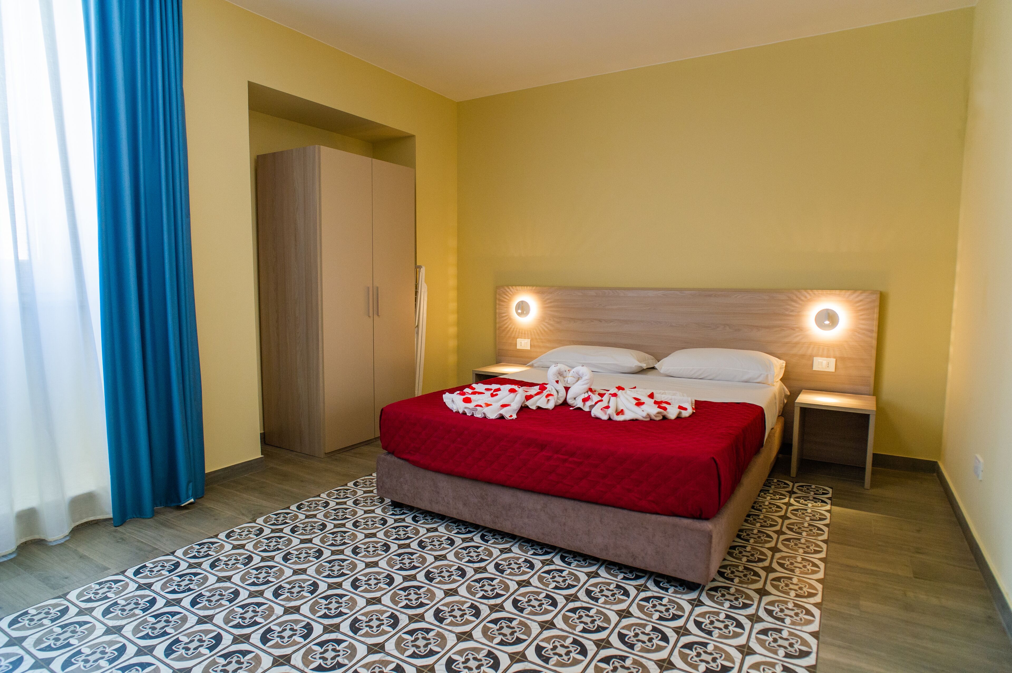 A bedroom with a bed, a nightstand, a wardrobe, and a patterned rug.