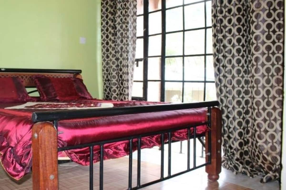 A room with a bed, a window with a view, and patterned curtains.