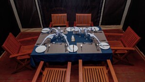 Un tavolo da pranzo imbandito per sei persone, con tovaglia blu e sei sedie in legno.