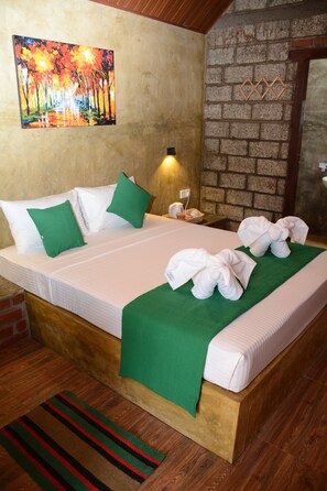 A neatly made bed with green pillows, a green throw blanket, and white towels arranged on the bed. - The Nature Villa and Cabanas (Negombo)