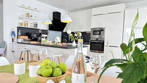 Een moderne keuken met witte kasten, een centraal eiland en een eethoek met een tafel voor twee personen.