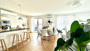 Een moderne keuken met een eethoek, houten vloeren en een grote groene plant.