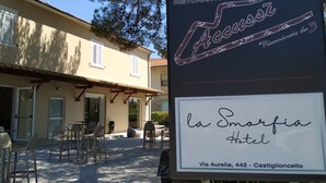 A sign for a restaurant named "Accuasi" with a restaurant logo and a sign for "La Smorfia Hotel" below it, including the address. - Hotel La Smorfia (Rosignano Marittimo)