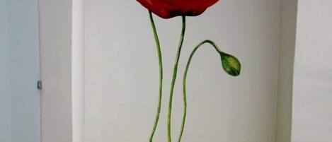 A room with a wall mural of a red poppy and a bright yellow chair.