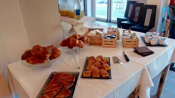 Ein reichhaltiges Buffet mit verschiedenen Speisen, darunter Gebäck und Desserts, auf einer weißen Tischdecke.