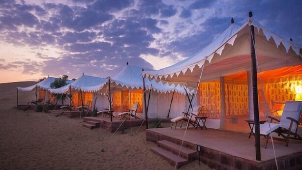 A row of tents with a covered seating area and steps leading up to the entrance. - Jaisalmer Khodiyar Resort - Campsite (Jaisalmer)