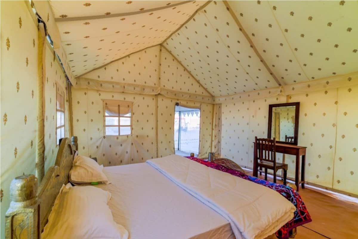 A tent-style room with a bed, a chair, and a mirror.