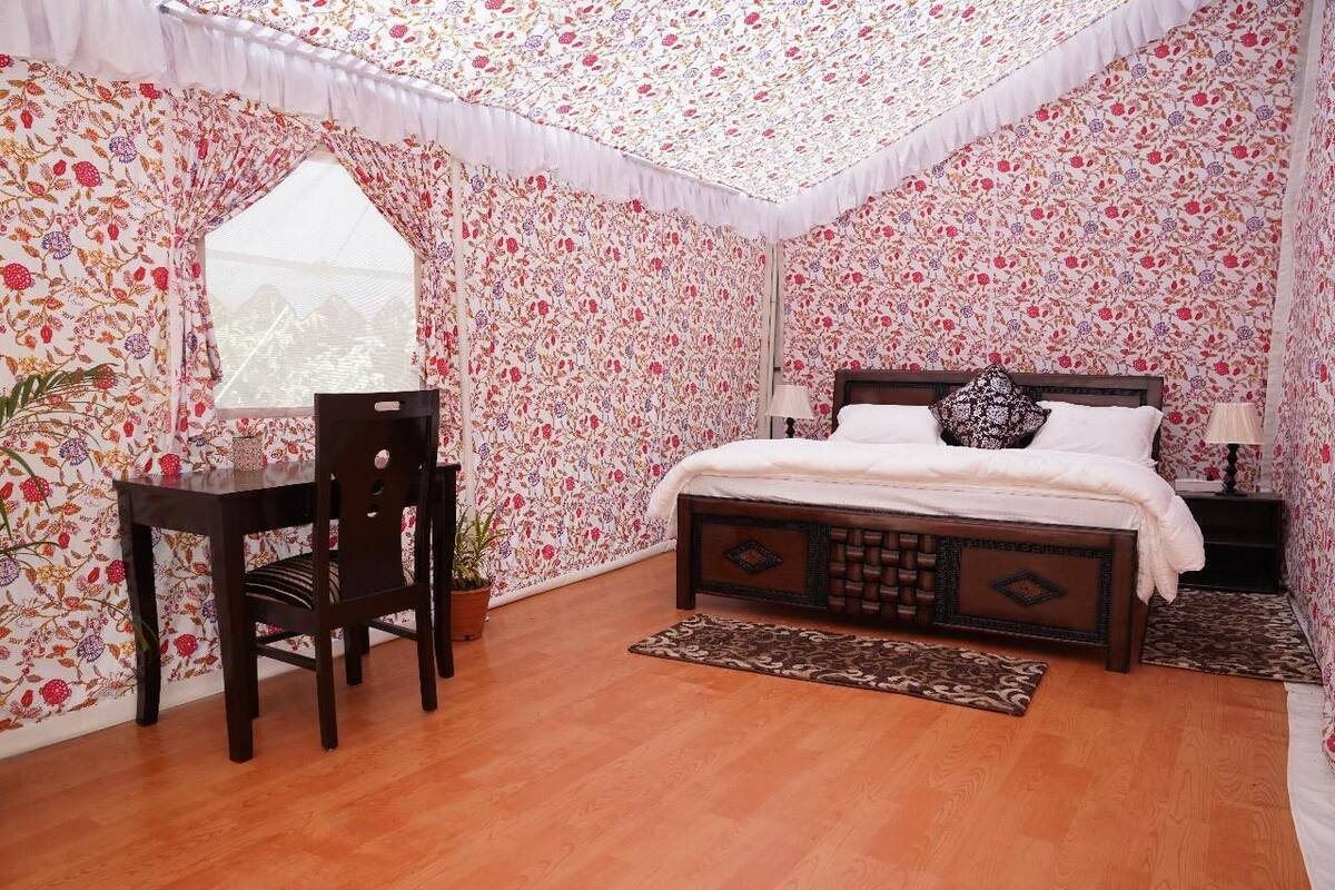 A bedroom with a wooden bed, a desk, a chair, and a window.