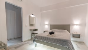 A modern bedroom with a bed, bedside tables, a mirror, and a wardrobe.