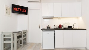 A modern kitchen with white cabinets, a built-in dishwasher, a small refrigerator, and a coffee maker.