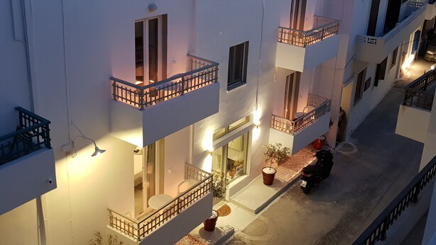 A multi-story building with balconies, a ground-level entrance, and a parked scooter.