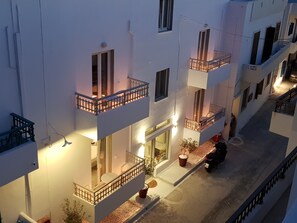 A multi-story building with balconies, a ground-level entrance, and a parked scooter.