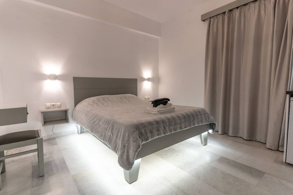 Ein modernes Schlafzimmer mit einem Bett, Nachttischen und einem Sessel.