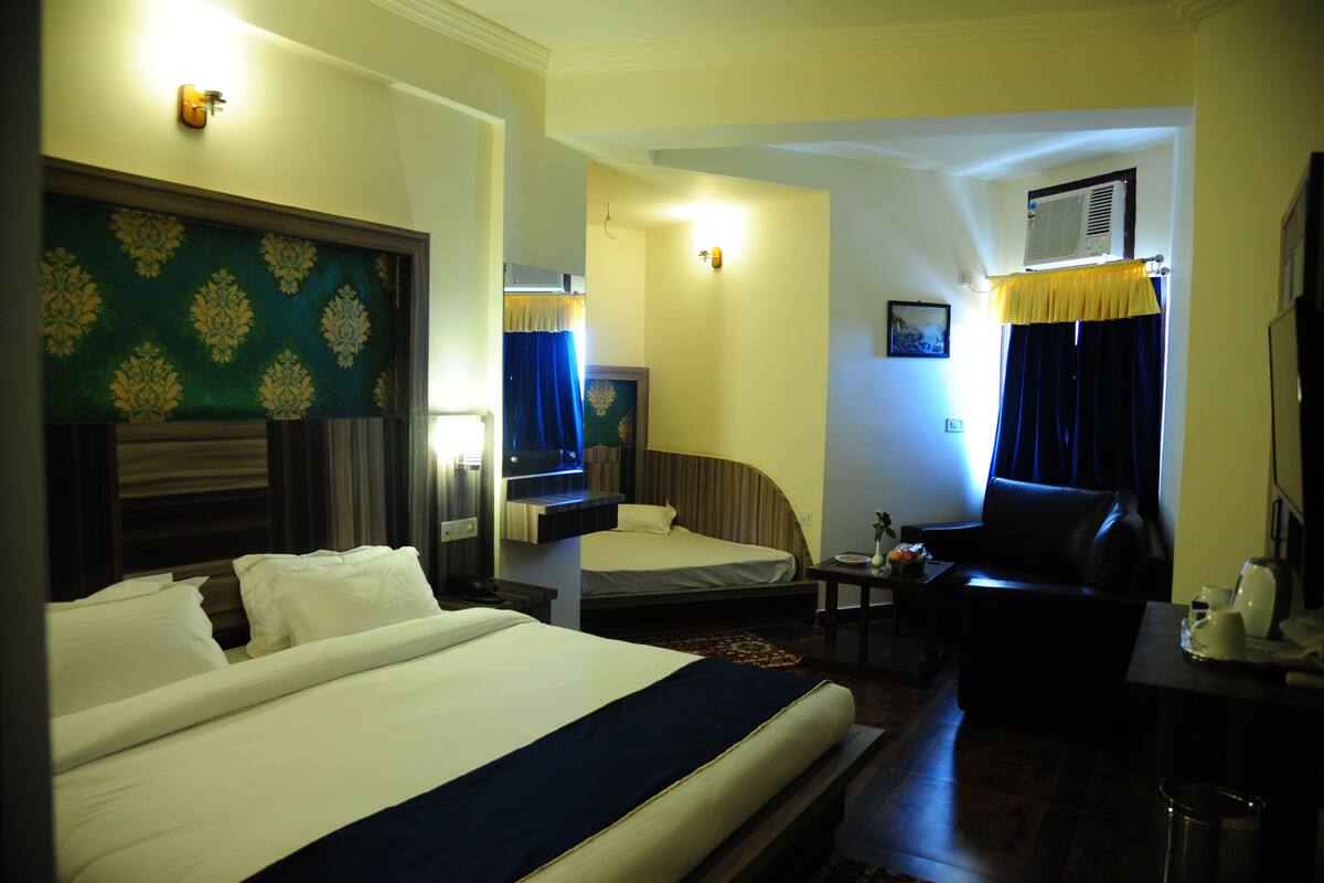 A hotel room with a large bed, a sofa, a desk, and a TV.