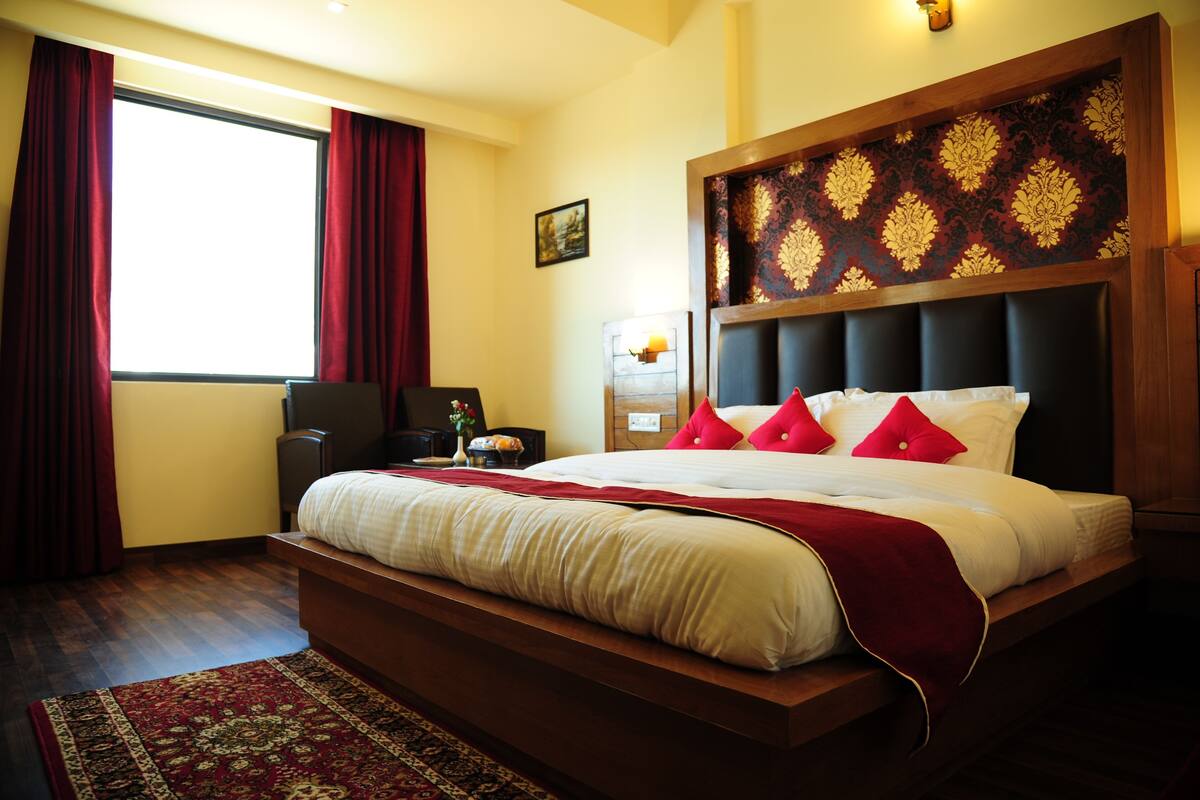 A large bed with a wooden headboard, red and white bedding, and a red throw blanket.