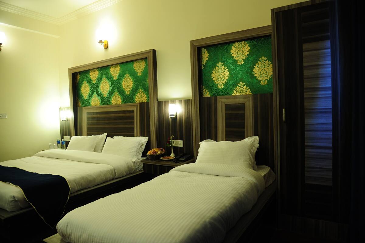 A hotel room with two beds, each with a headboard and a nightstand.