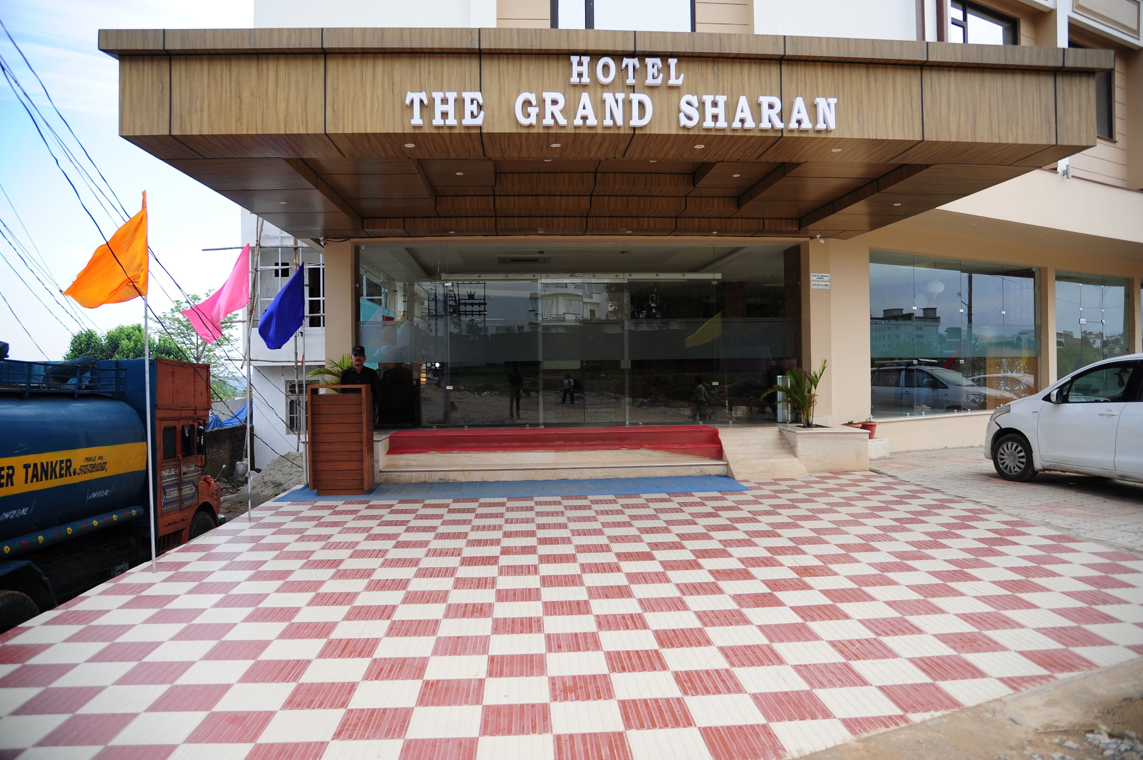 The entrance of Hotel The Grand Sharan with a checkered floor and a sign above the entrance.