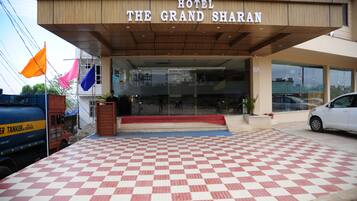 The entrance of Hotel The Grand Sharan with a checkered floor and a sign above the entrance.