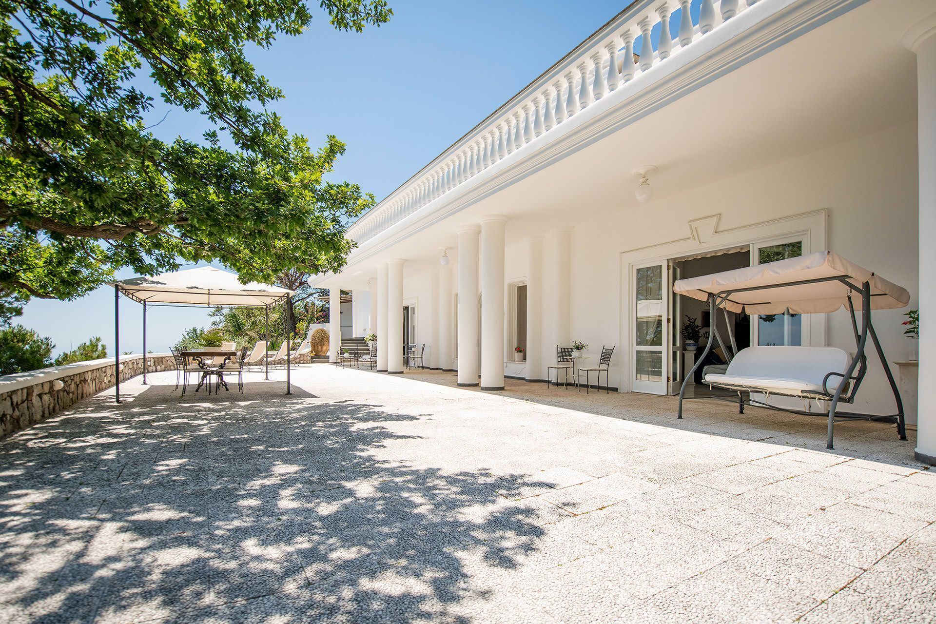 A covered outdoor patio with seating, columns, and a pergola.