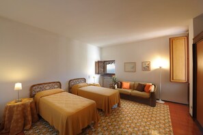 Habitación de hotel con dos camas, un sofá, un radiador y vistas al mar.