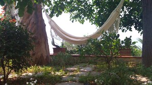 A hammock hanging between trees in a garden with stone steps and potted plants. - Casa Giardino (Positano)