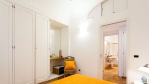 A bedroom with a bed, wardrobe, and a bathroom visible through an open door. - Casa Dorothea 2 (Positano)
