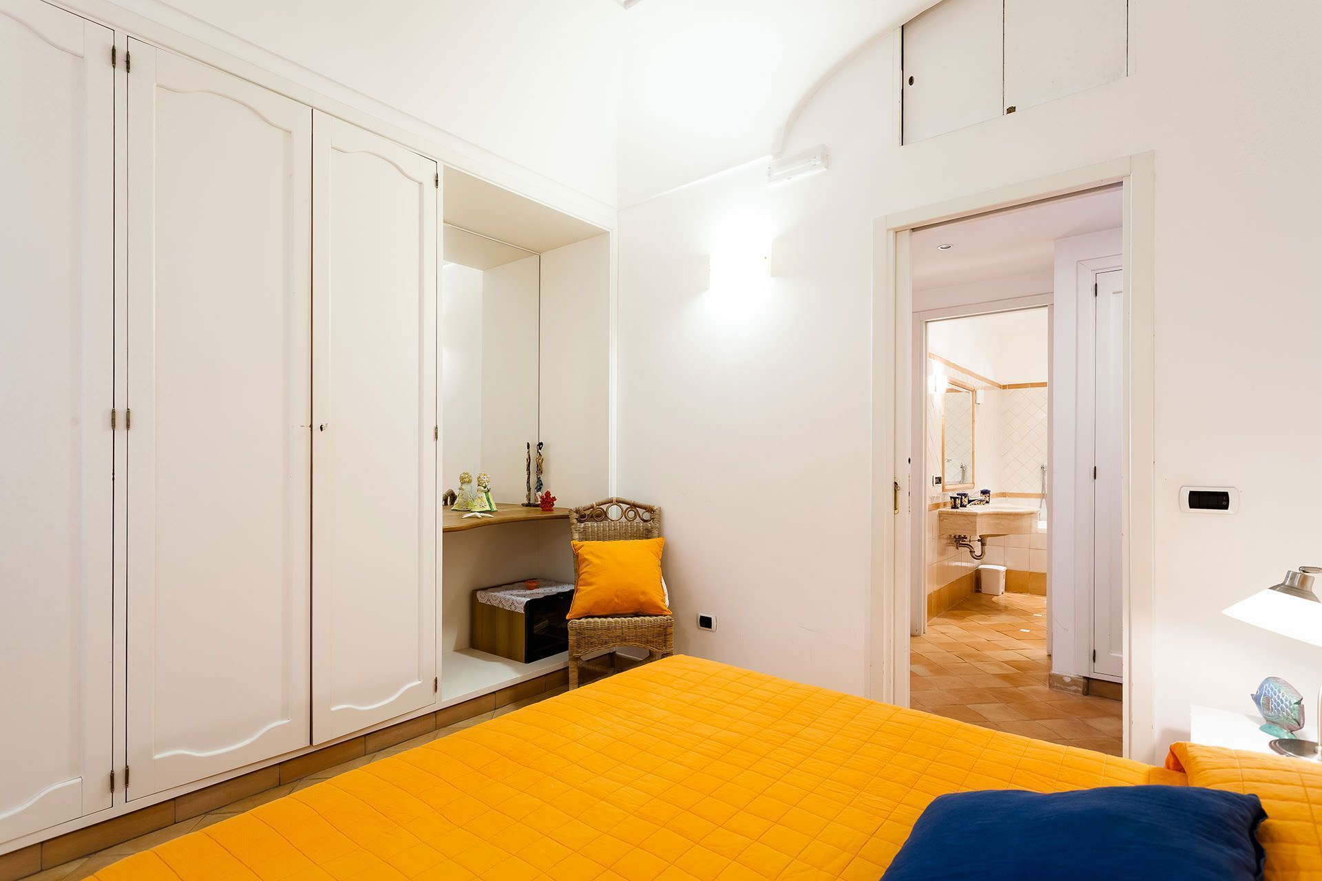 A bedroom with a bed, wardrobe, and a bathroom visible through an open door.