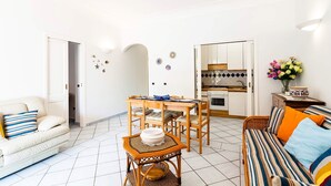 A compact living space with a dining area, kitchenette, and seating arrangements. - Casa Dorothea 3 (Positano)