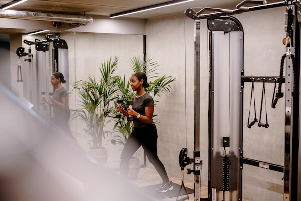 Un gimnasio con equipamiento de ejercicio, un espejo y plantas en macetas.