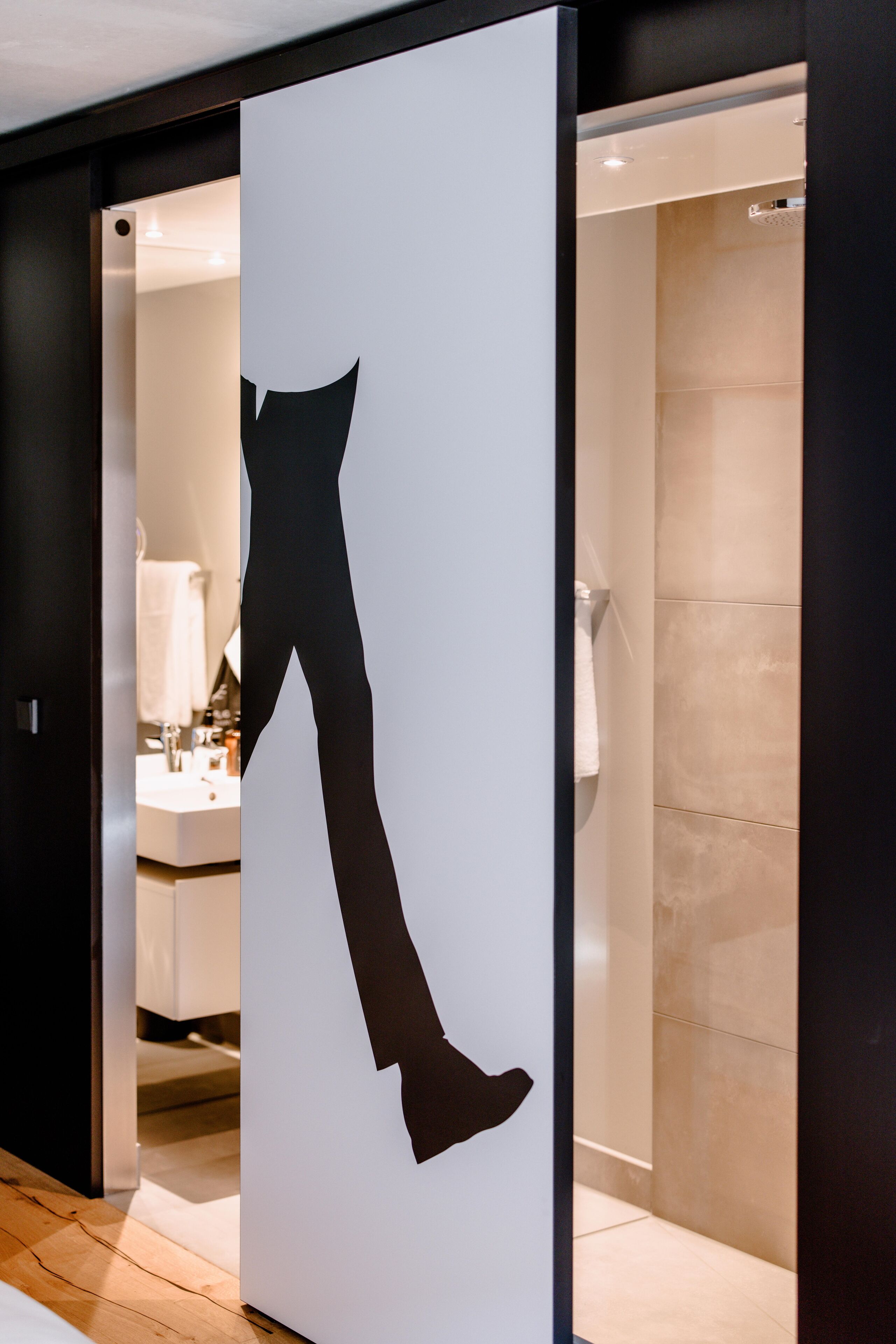 Een modern interieur met een grote spiegel die een badkamer en een witte muur met een zwart silhouet weerspiegelt.