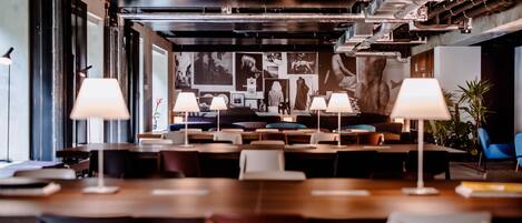 Un área de comedor moderna con mesas, sillas e iluminación ambiental.