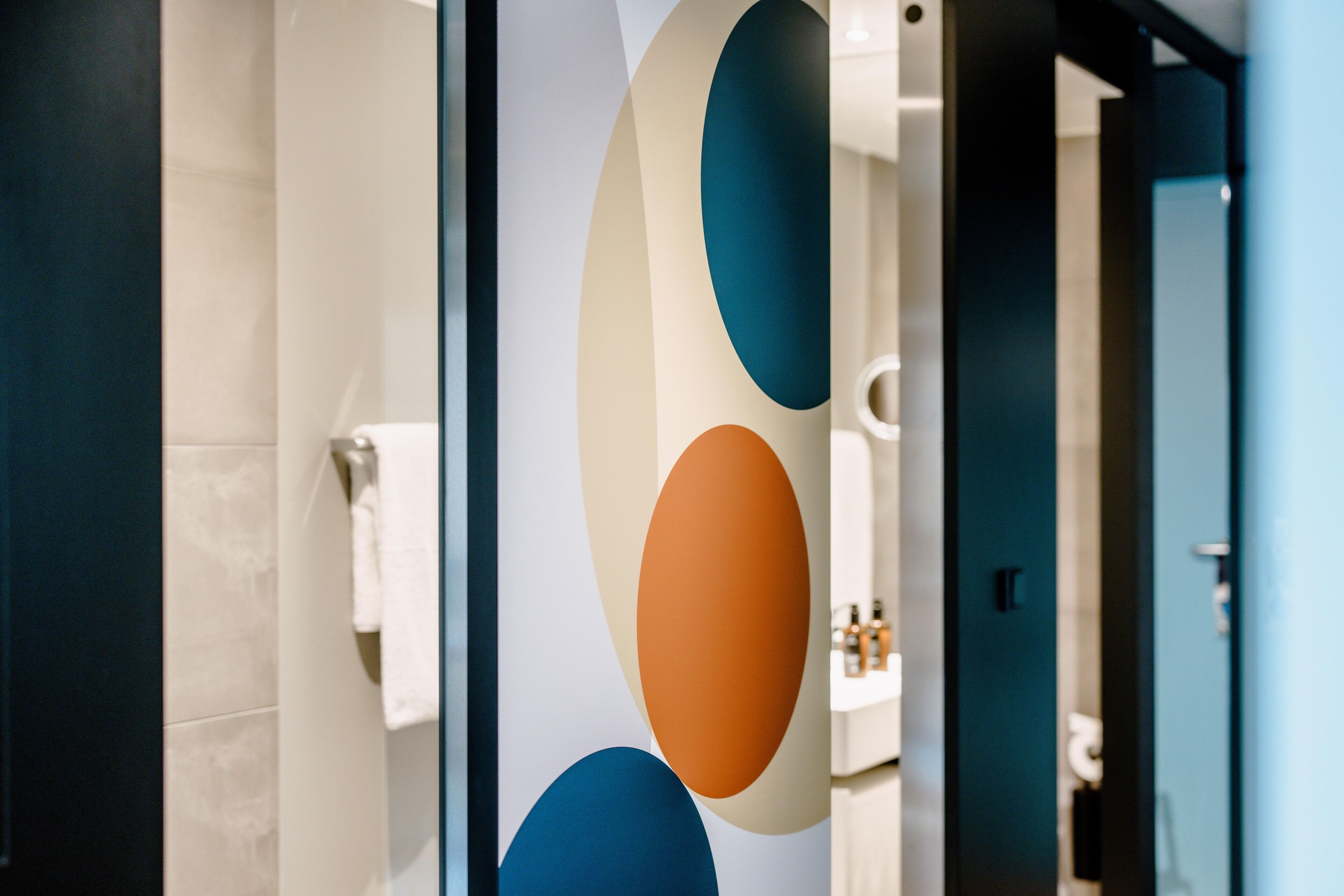 Een badkamer met een modern design, voorzien van een grote spiegel, een handdoekhouder en een wastafel met toiletartikelen.