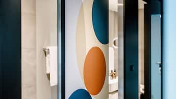 Een badkamer met een modern design, voorzien van een grote spiegel, een handdoekhouder en een wastafel met toiletartikelen.