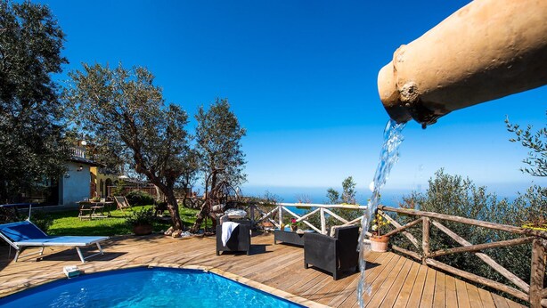 A wooden deck with a pool, lounge chairs, and a pergola with a water feature. - Villa Pandora (Sorrento)