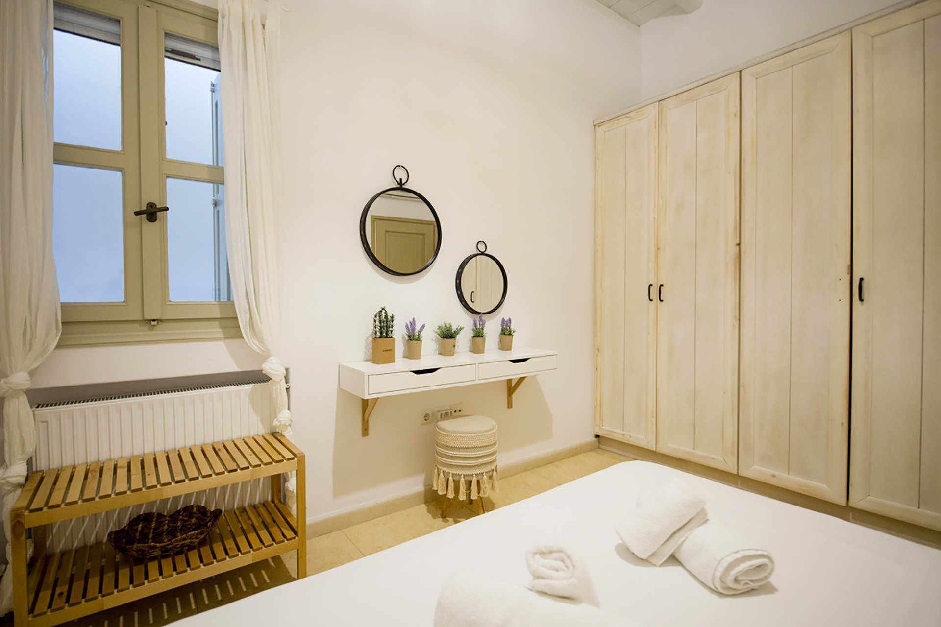 Una camera da letto con un letto, una mensola in legno con piante, uno specchio e un armadio.