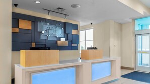 A reception desk with a modern design, a wall-mounted digital display, and a large window providing natural light. - Holiday Inn Express & Suites Leander by IHG (Leander)