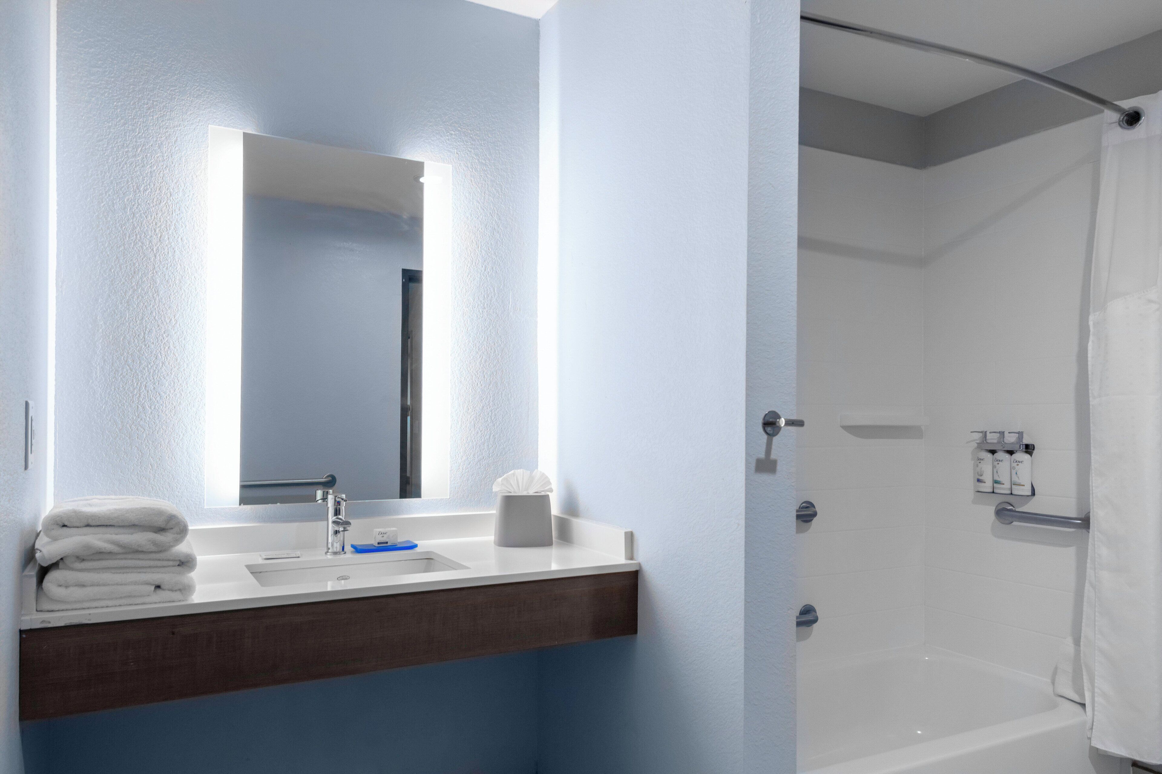 A modern bathroom with a white sink, mirror, and shower.