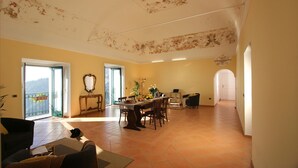 Amplia sala de estar con mesa de comedor, sillas y un balcón con vistas.