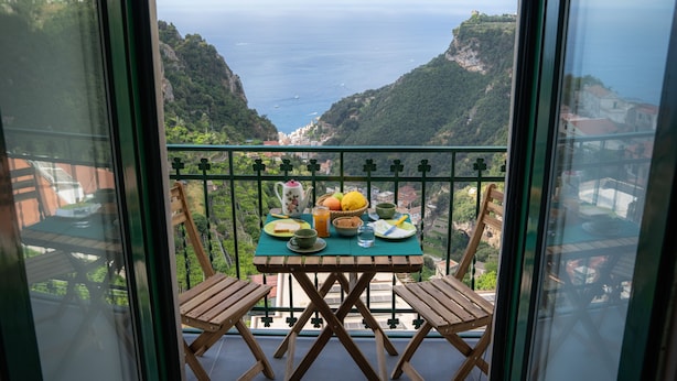 Un balcón con mesa dispuesta para el desayuno, con vistas a un paisaje costero.
