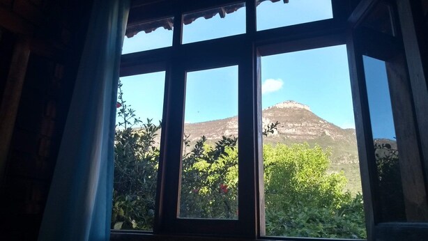 A window with a view of a mountain and greenery. - Pousada Casa Da Trilha (Palmeiras)