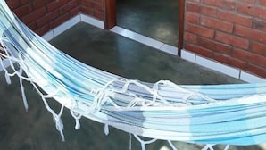 A room with a bed, a hammock, and a brick wall. - Pousada Casa Da Trilha (Palmeiras)