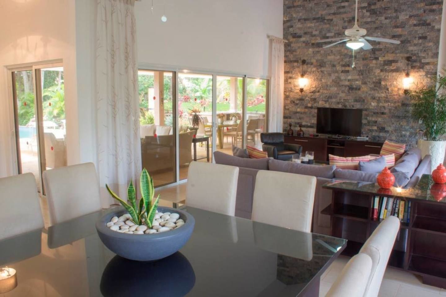 A modern living room with a glass dining table, a sofa, and a TV.