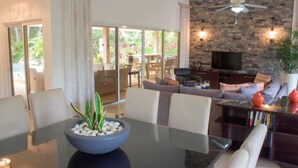 A modern living room with a glass dining table, a sofa, and a TV. - Exquisite Taste Awaits you With This Custom Styled Villa (Sosúa)