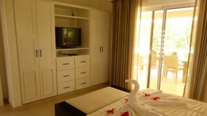 A hotel room with a bed, a TV on a cabinet, and a balcony with curtains. - Exquisite Taste Awaits you With This Custom Styled Villa (Sosúa)