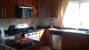 Cocina con armarios de madera, microondas, estufa y lavavajillas.